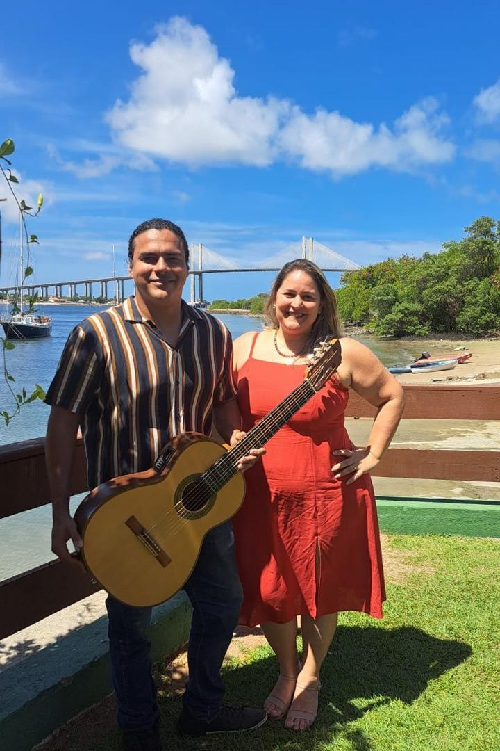 Duo acústico: voz e violão, com a Ponte Newton Navarro ao fundo